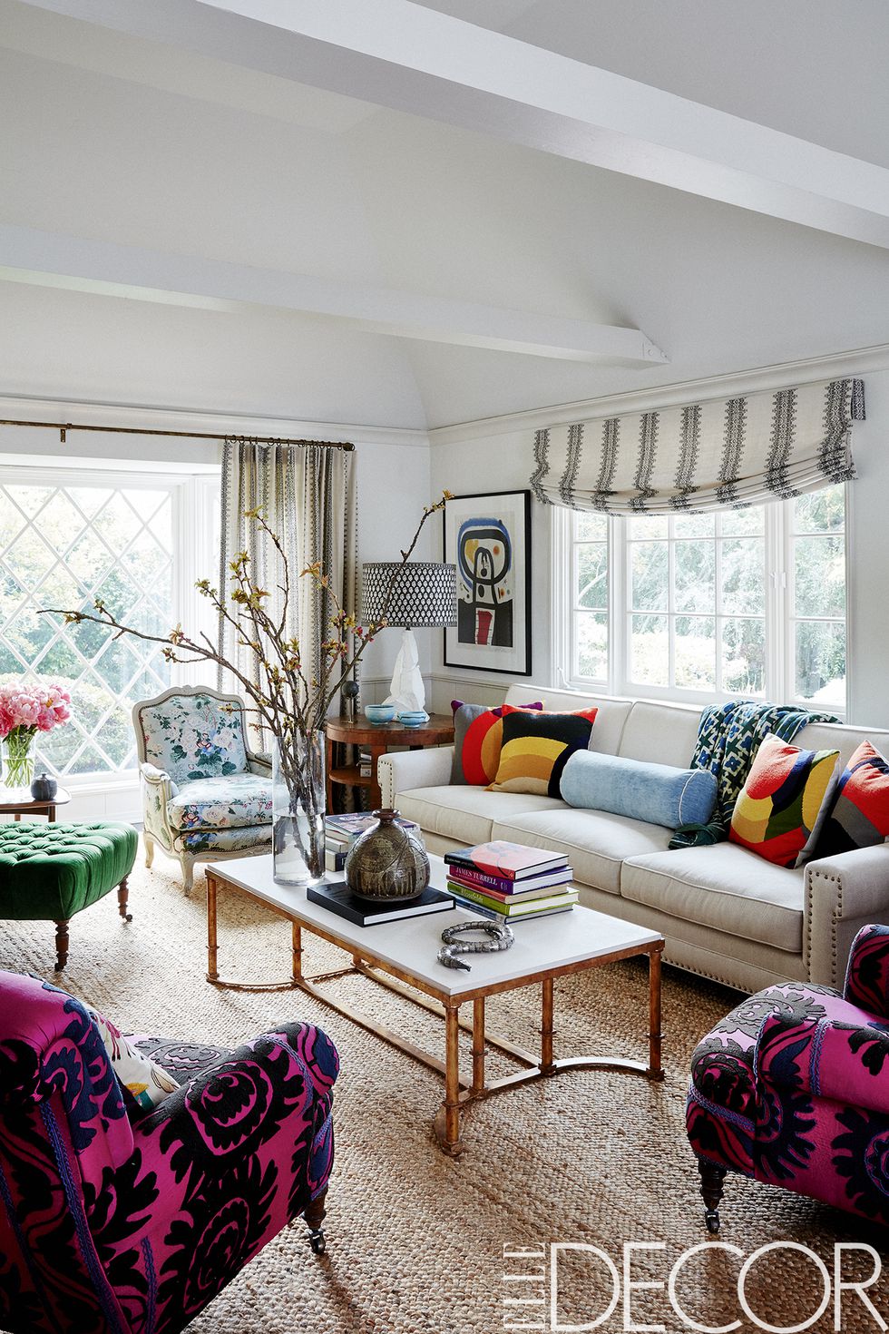 The living room sofa is covered in a Schumacher fabric , the cocktail table, the 1940s Italian walnut side table, the lamp and the jute rug are all from Hollywood at Home . The ’50s French bergère is covered in a Lee Jofa floral and vintage French armchairs are upholstered in a 1960s suzani.