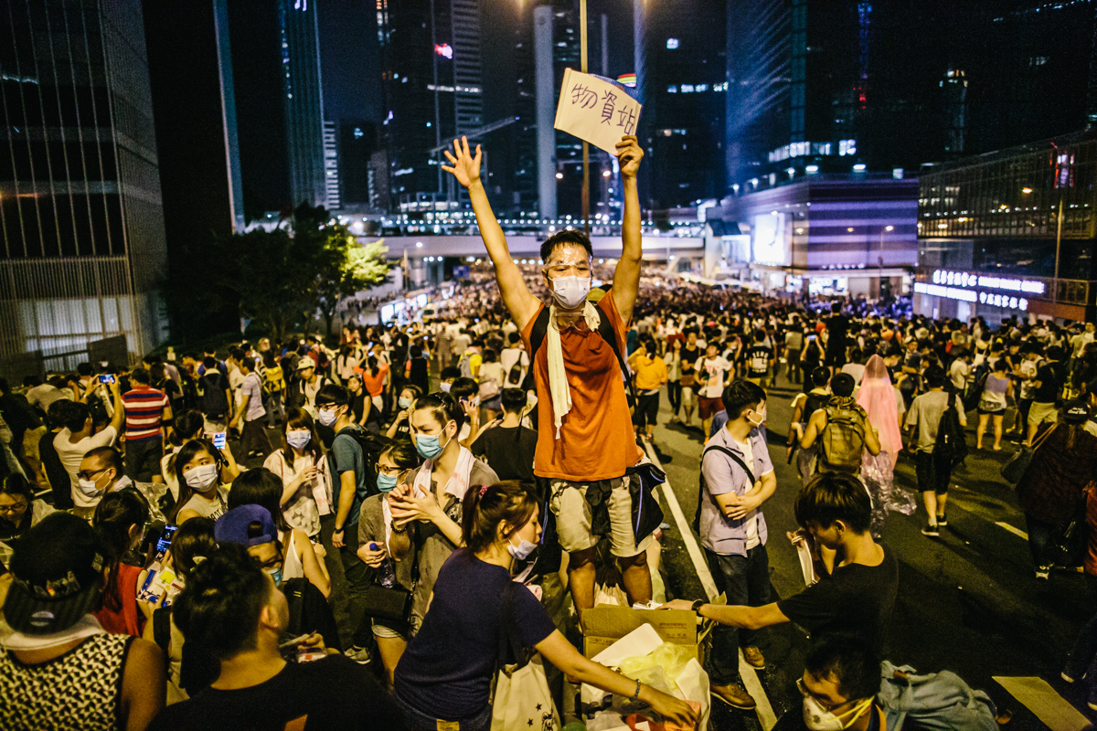 14.09.28 - Hong Kong: Protestors outside the government’s headquarters in Admiralty have taken over Harcourt Rd. Police conduct a clearance operation using tear gas. A man holds up a sign saying “supplies’.