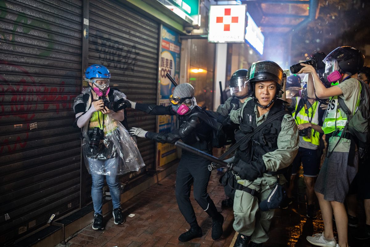 Protestor is arrested while reaching for help from photographer and police man looks satisfied to me.