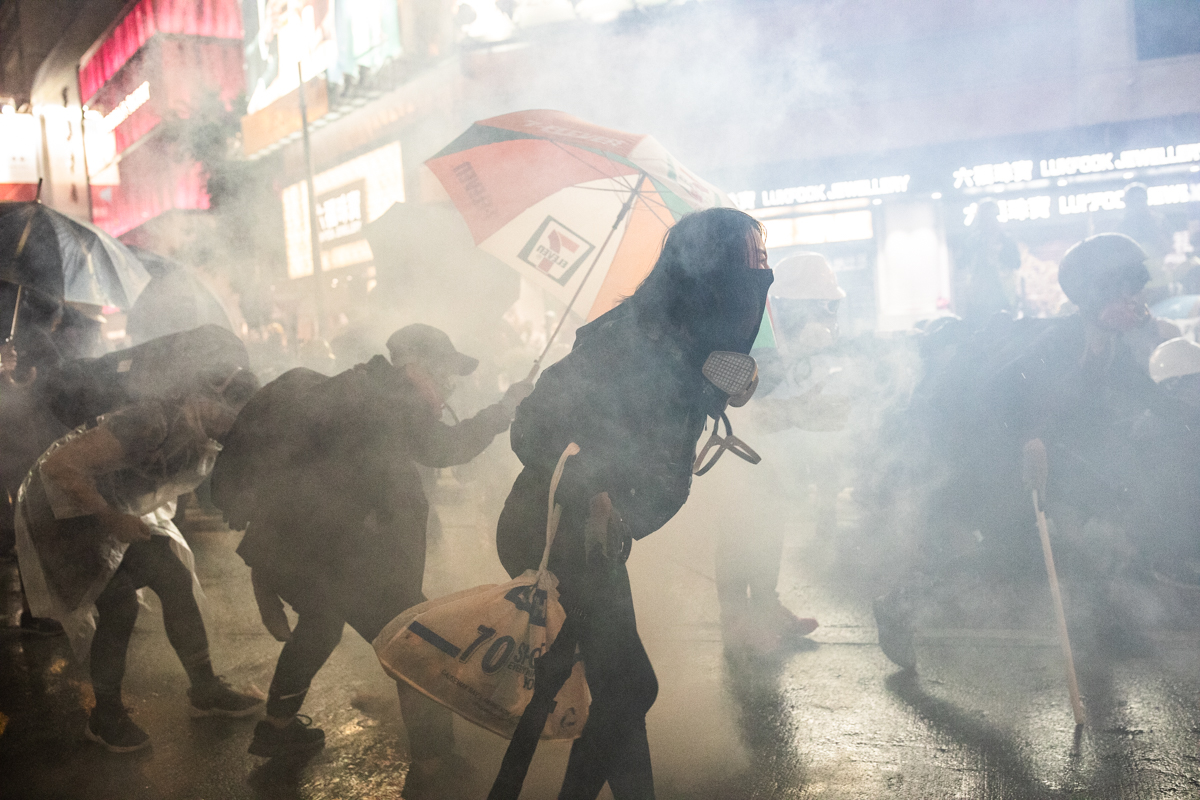 Protestor with no mask on in tear gas cloud.