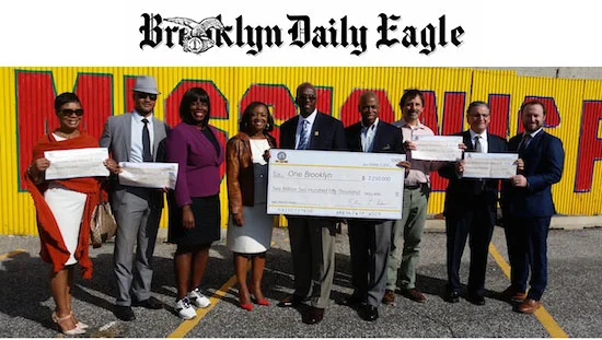 Brooklyn Borough President Eric Adams, fourth from right, and several elected officials, community activists and developers' representatives display a mock check for $2,250,000 as Adams announces his Faith-based Development Initiative in the parking lot of Calvary Community Church in Crown Heights. Eagle photo by James Harney