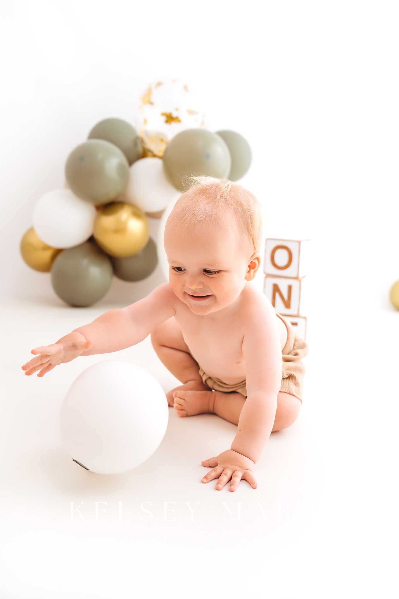 baby boy playing with a white balloon with one blocks in the background