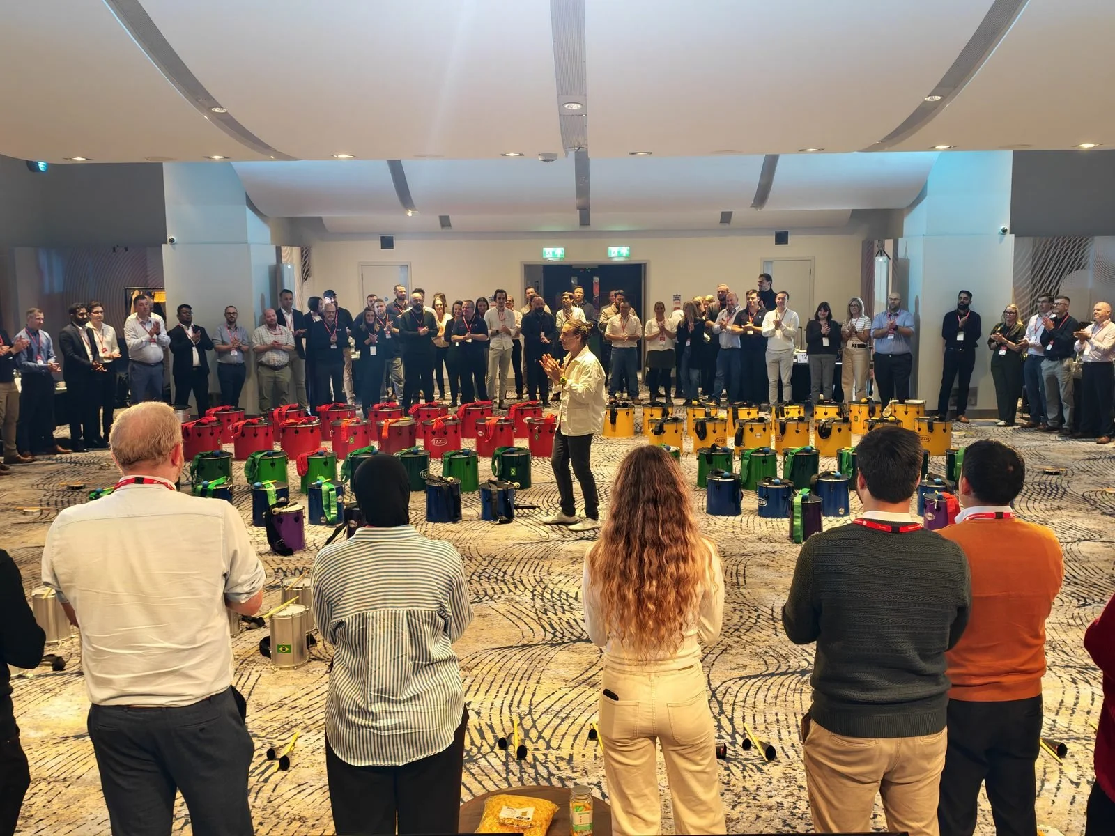 Conference delegates gathered around a circle of colourful drums for a drumming team building session