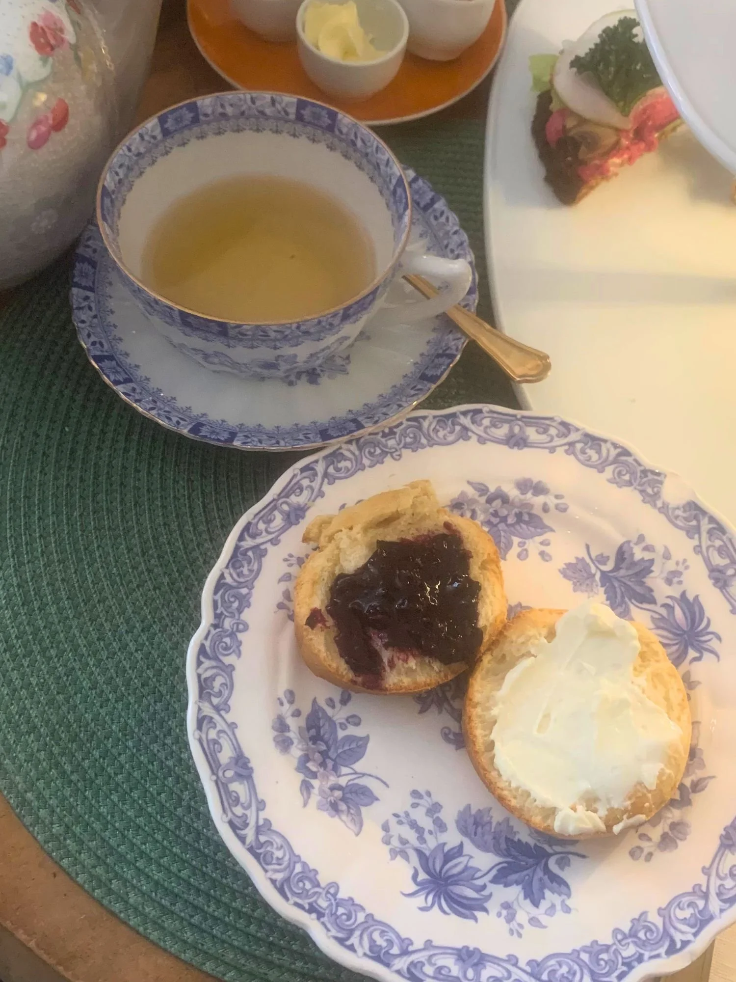 Blue-and-white vintage china with tea and freshly baked scones topped with jam and cream at an afternoon tea at Alice och Kattens Tesalong in Lund, Sweden.