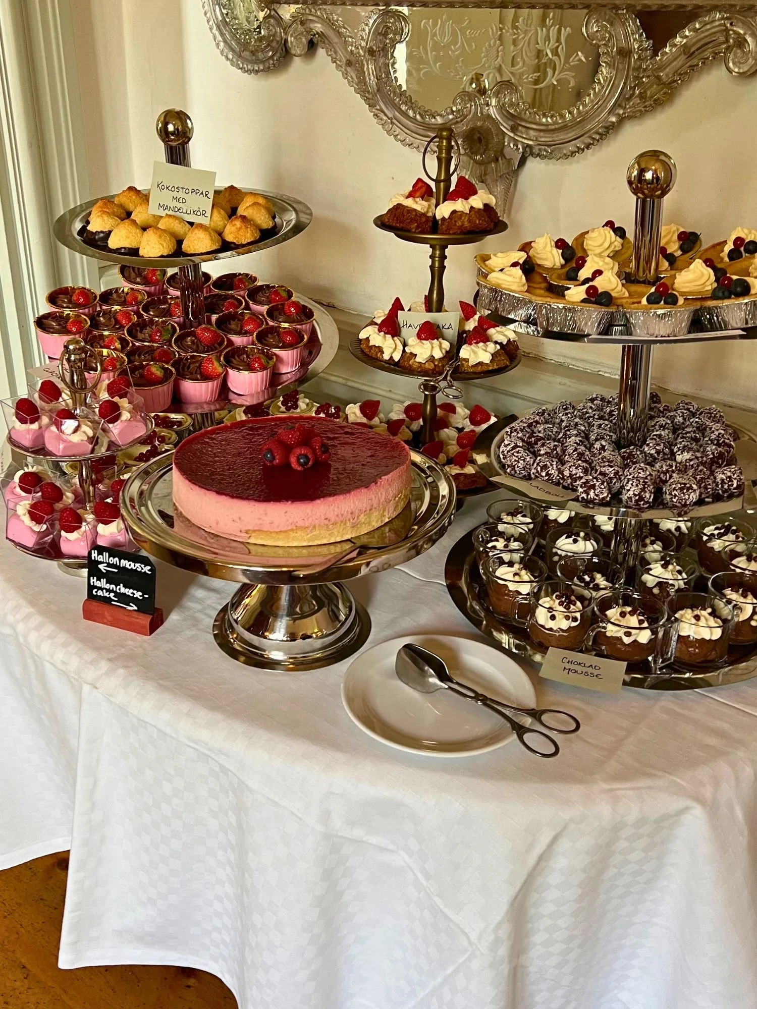 An elaborate dessert buffet table covered in a white tablecloth at afternoon tea at Vadstena Klosterhotel.