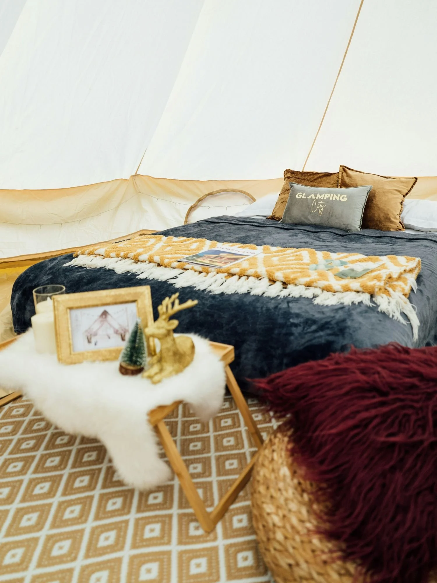 The interior of a cozy, white canvas bell tent set up for luxury camping.