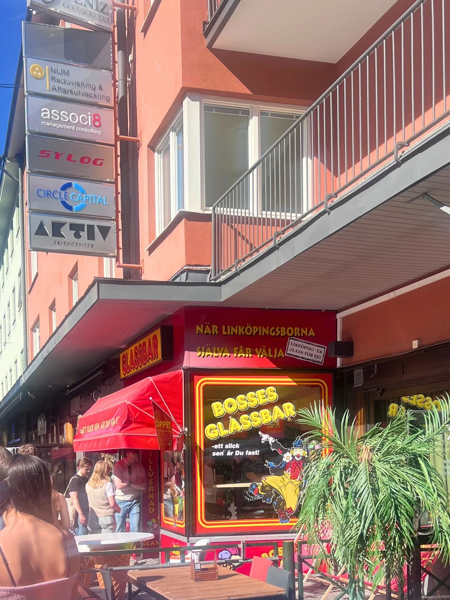 The red exterior storefront of Bosses Glassbar ice cream shop in Linköping, featuring retro yellow signage and a cartoon clown window display.