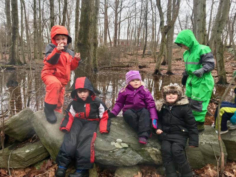 Forest Preschool children playing on the stone wall near the Con Edison STEM Challenge Course.