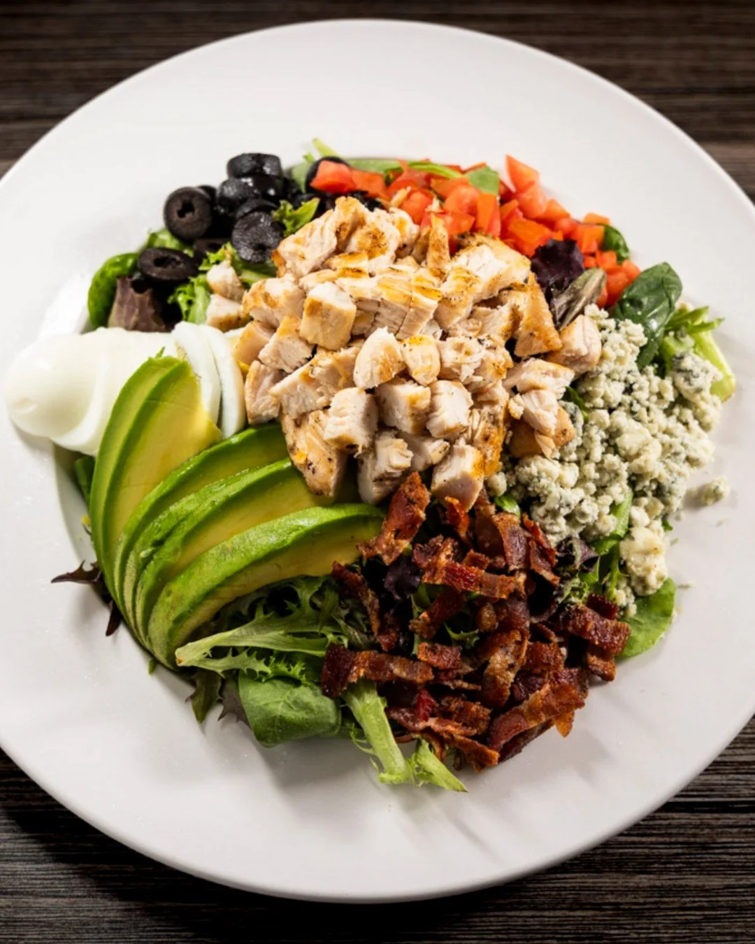 🥗 Freshen up your meal with our H.T. Chicken Cobb Salad! 
A delicious blend of mixed greens, grilled chicken, avocado, crispy bacon, ripe tomatoes, bleu cheese crumbles, black olives, and egg, all topped with your choice of dressing. Nutritious and