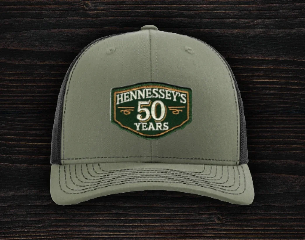 Green trucker hat featuring an embroidered Hennessey’s Tavern 50 Years anniversary logo patch on the front panel
