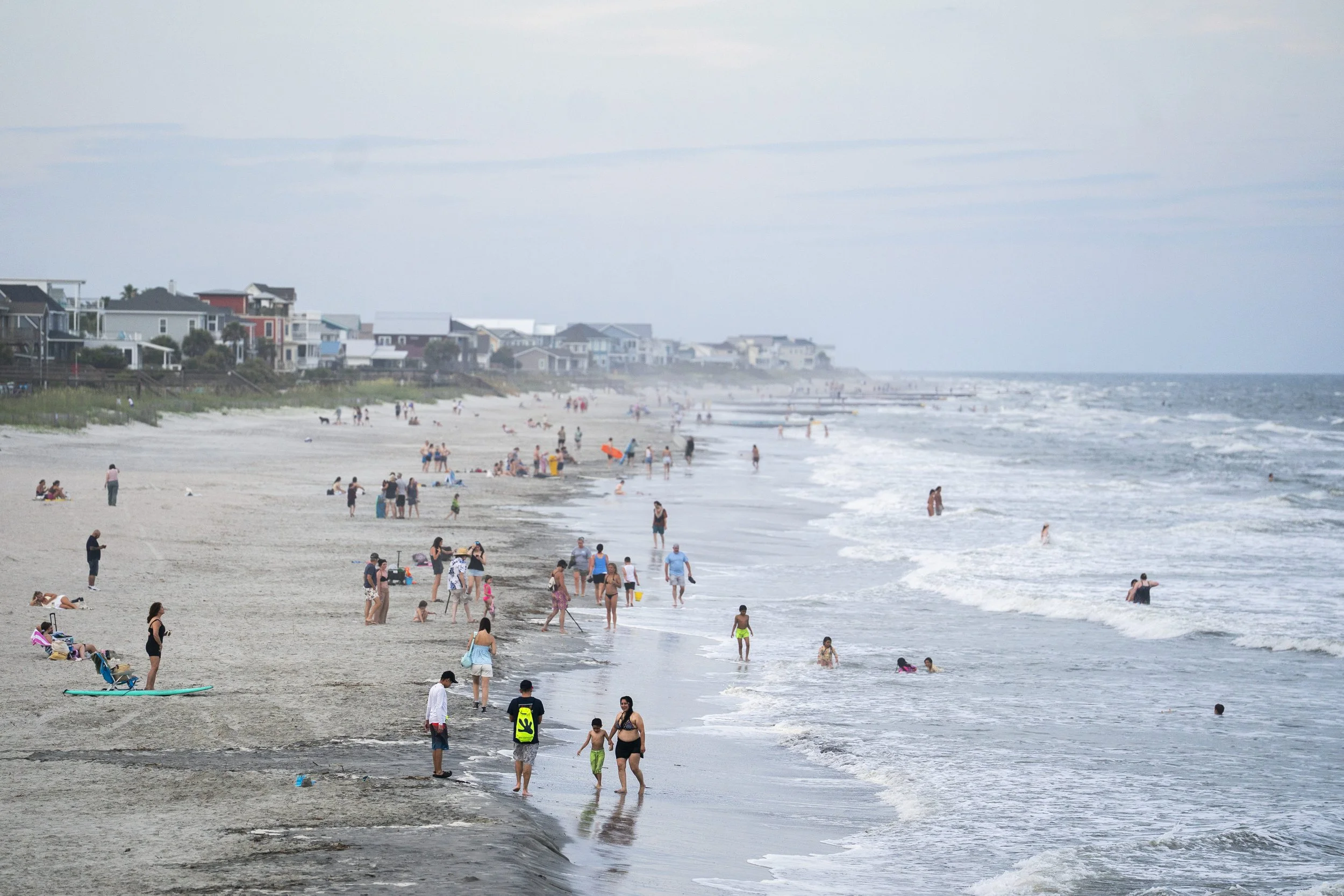 Moderately crowded beach and surf at Folly Beach