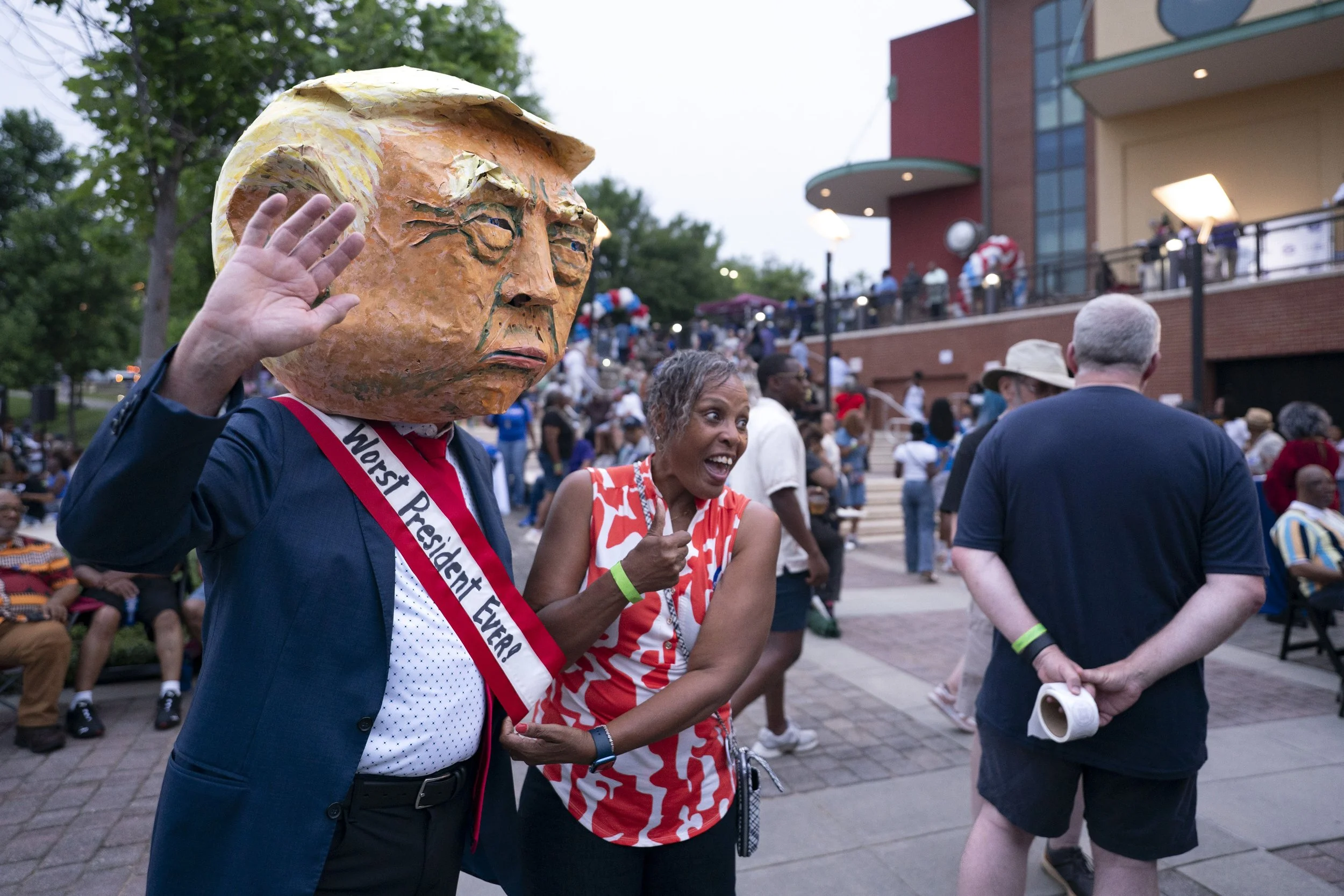 A person wearing a mask in the likeness of U.S. President Donald Trump  waves for a photo