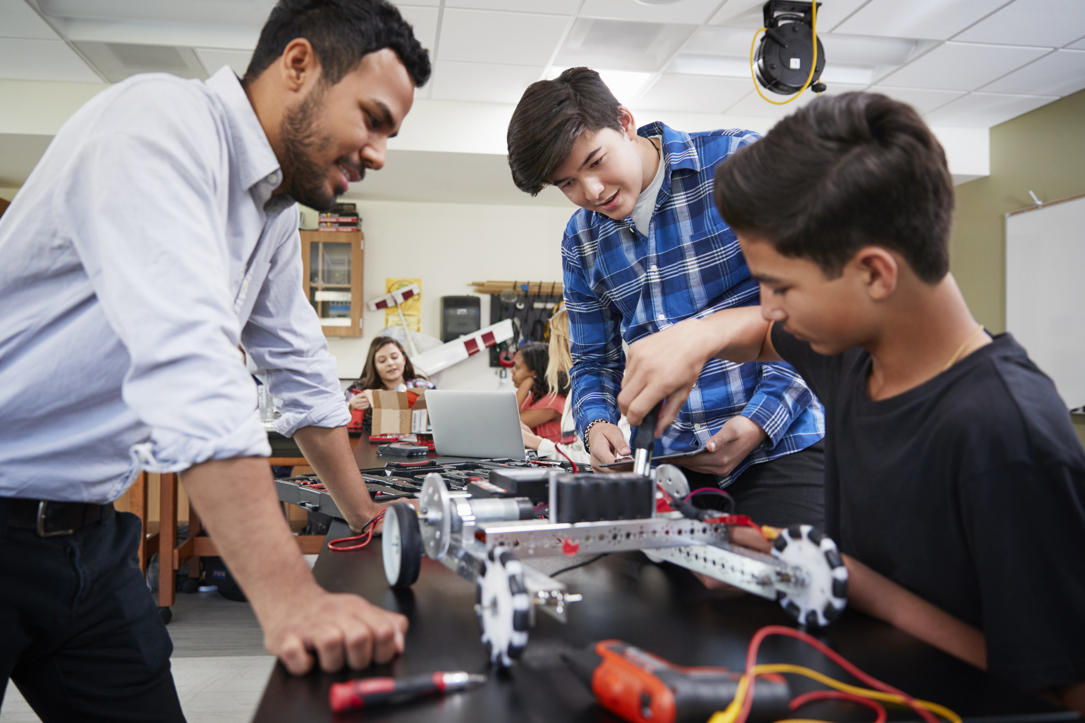 Teacher and students working on a robot.