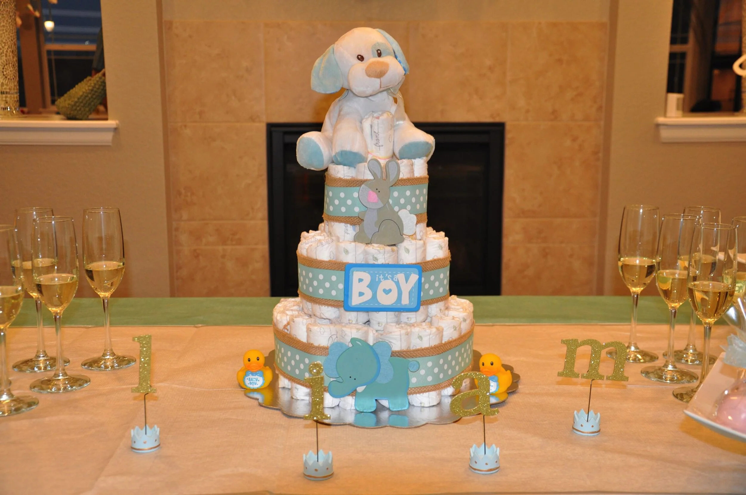 Diaper cake centerpiece featuring a plush dog, blue and white color scheme, decorated with baby-themed accents, for a baby shower event.
