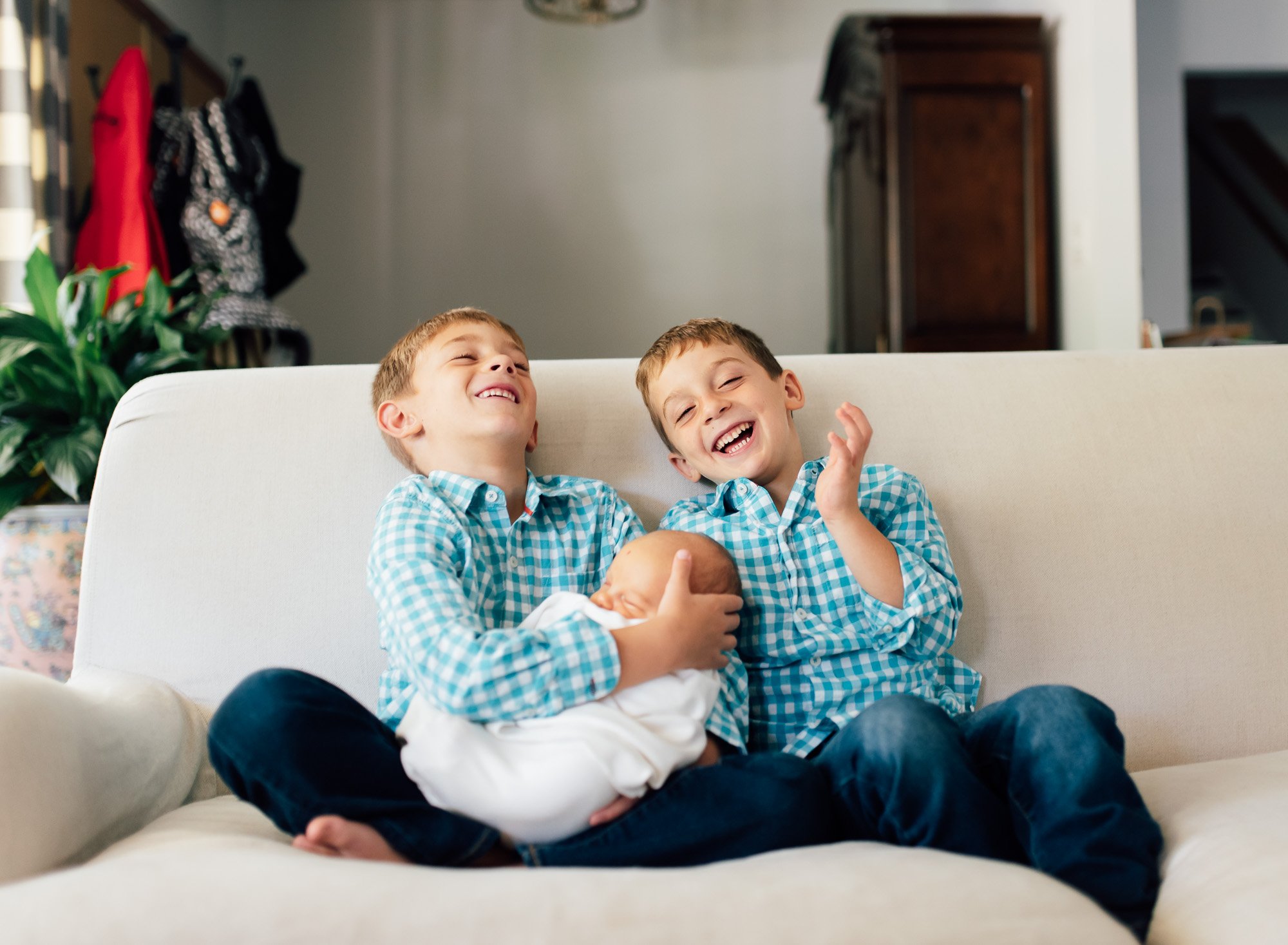 siblings laughing and holding newborn baby  St. Louis Newborn Photography sarahrowlandphotography.com