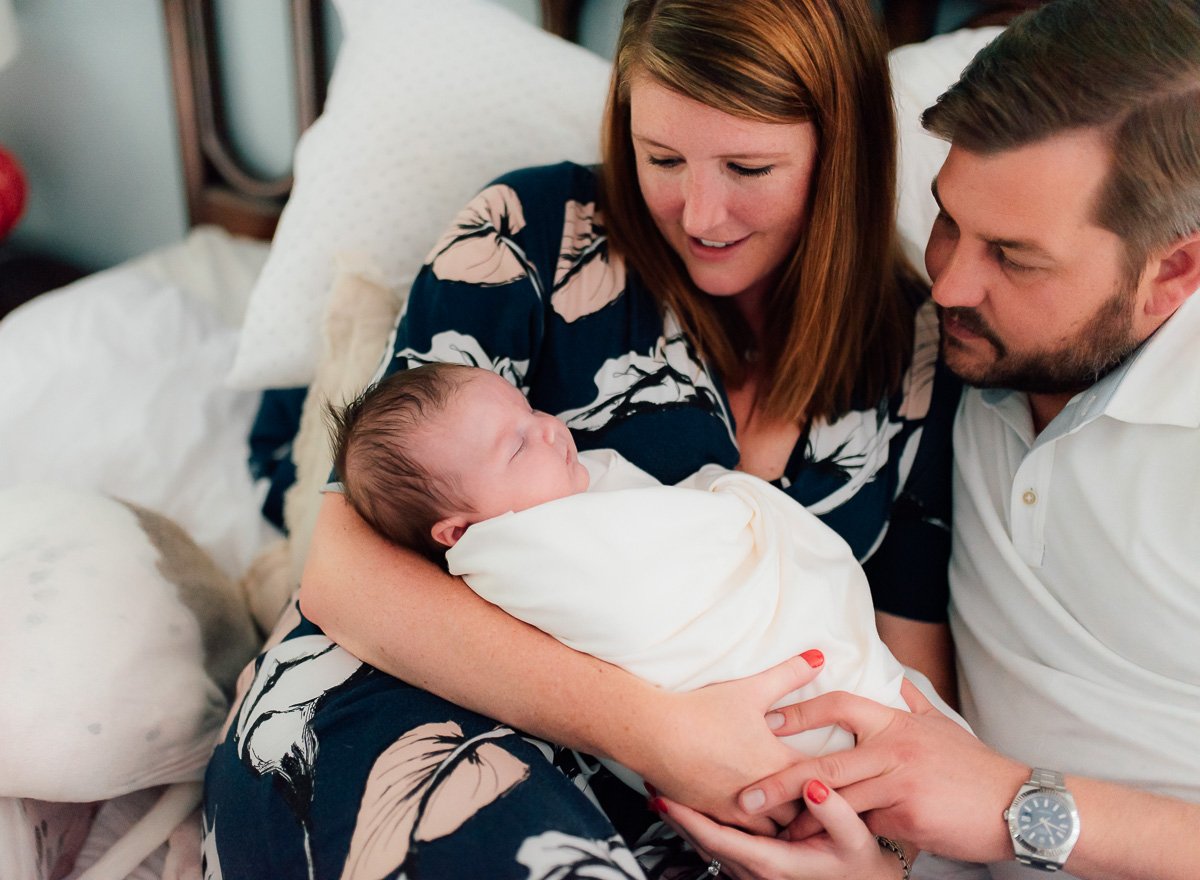 parents holding newborn baby on bed  St. Louis Newborn Photography sarahrowlandphotography.com