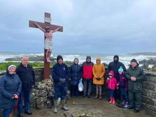 Fr Gerry McCloskey and worshippers gather beside a coastal crucifix