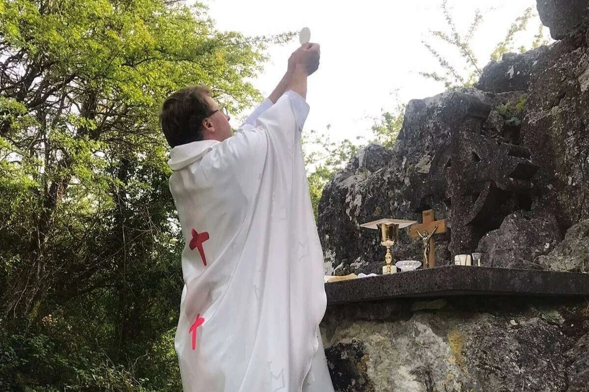 Fr Fergal Cummins raises the host at Clara Mass Rock