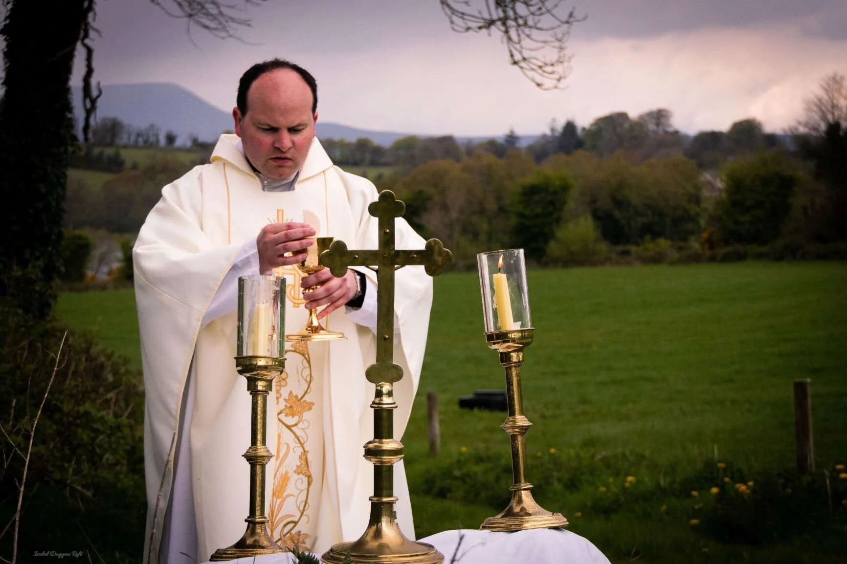 Fr Sean Maguire celebrates Mass at a candlelit outdoor altar in Kilmore