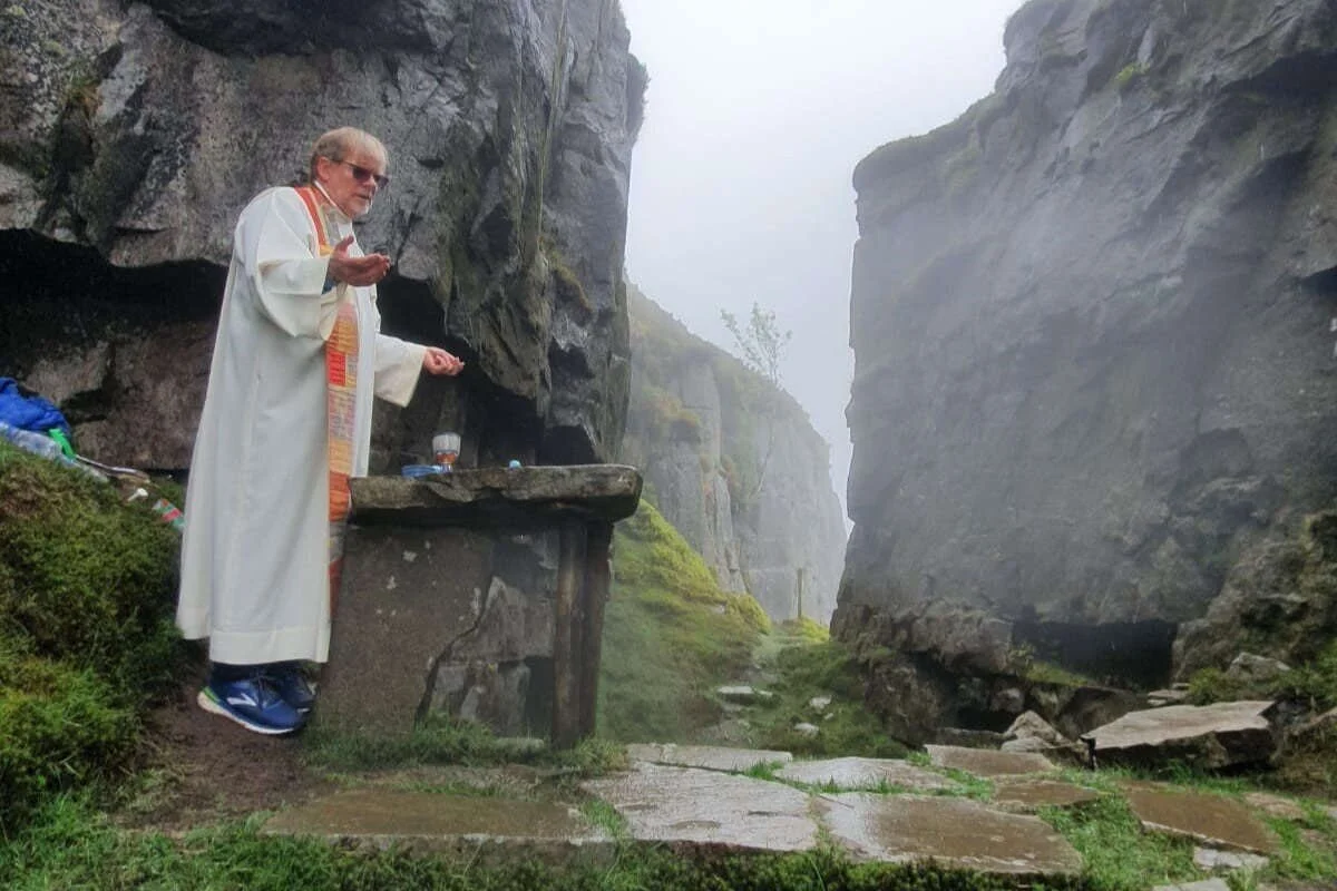 A priest celebrates Mass beside a tall rock face