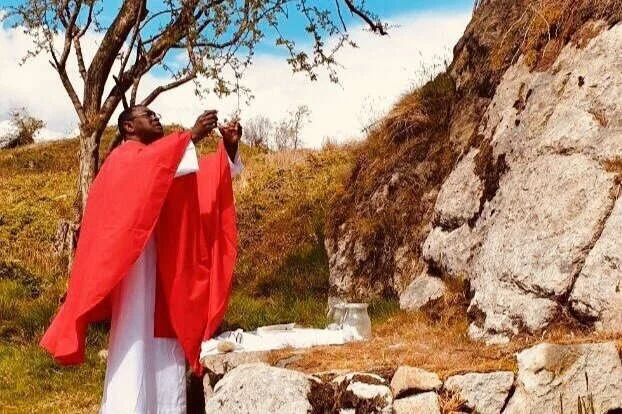 Fr Peter raises the host beside a Mass Rock in Armagh
