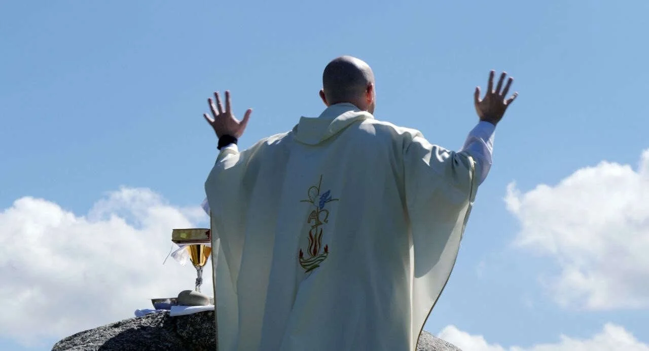 Fr Shane Gallagher prays with raised hands during outdoor Mass in Raphoe