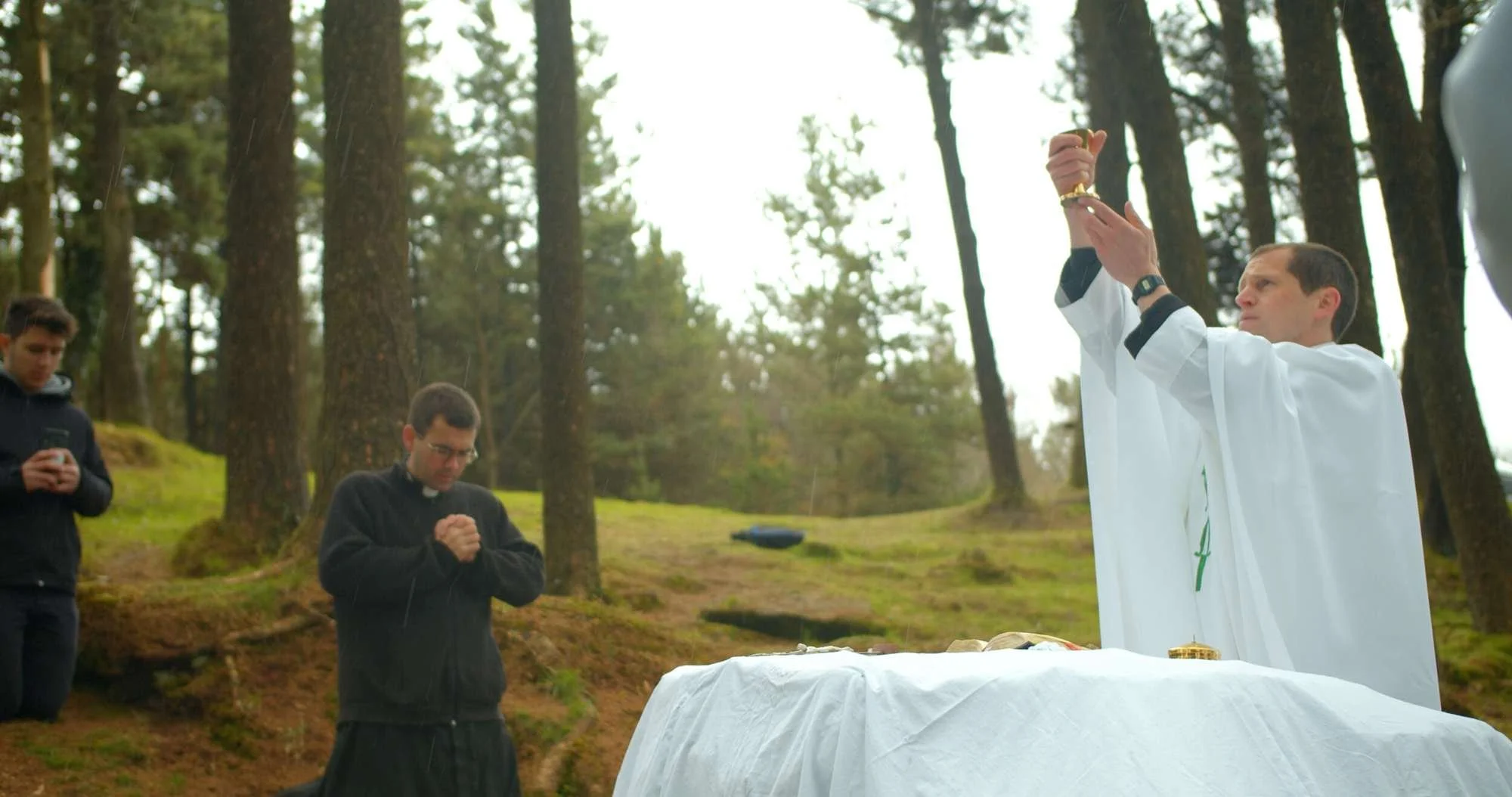 Fr Luke DeMasi raises the host at a woodland Mass Rock in Cloyne