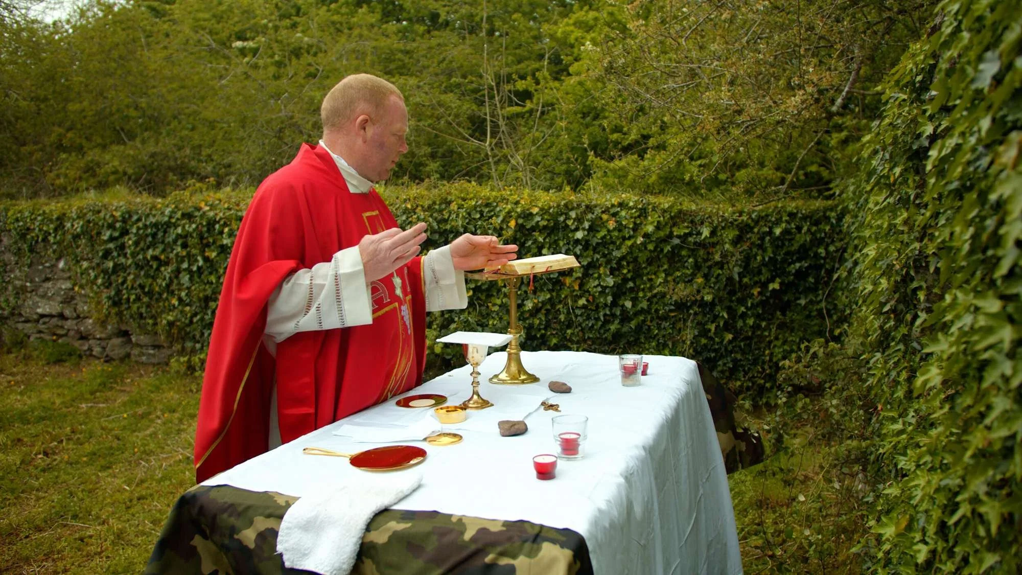 A priest celebrates Mass beside a chalice at a stone altar