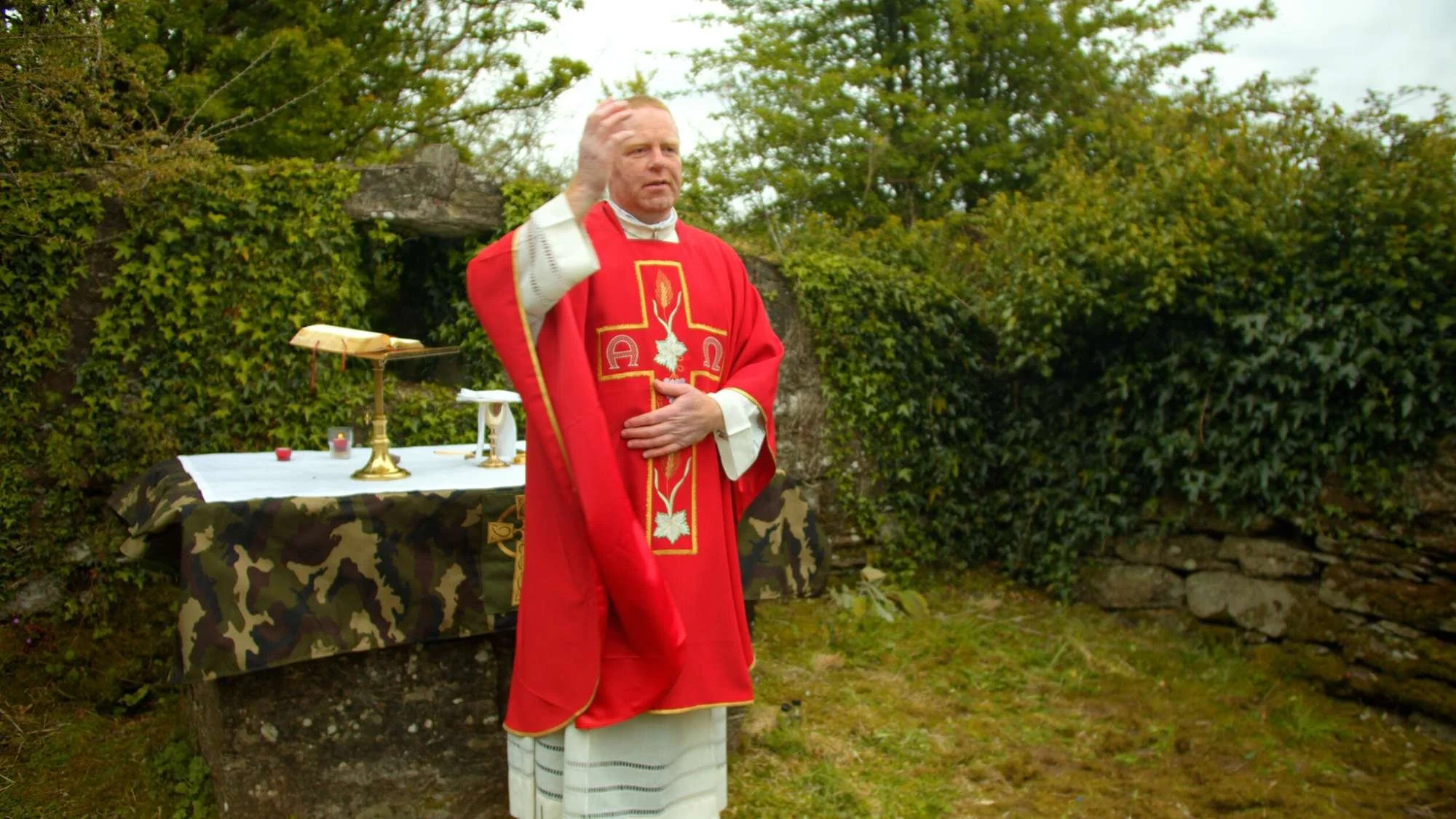 A priest addresses worshippers beside a woodland altar
