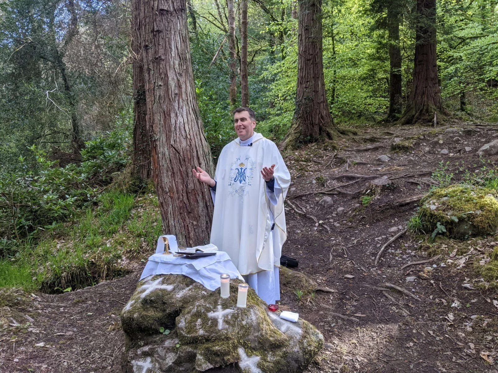 A priest stands behind a stone altar at Pike Wood Mass Rock