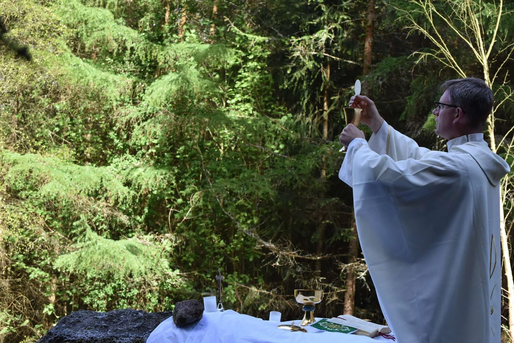 Fr Patrick Cahill raises the host during woodland Mass