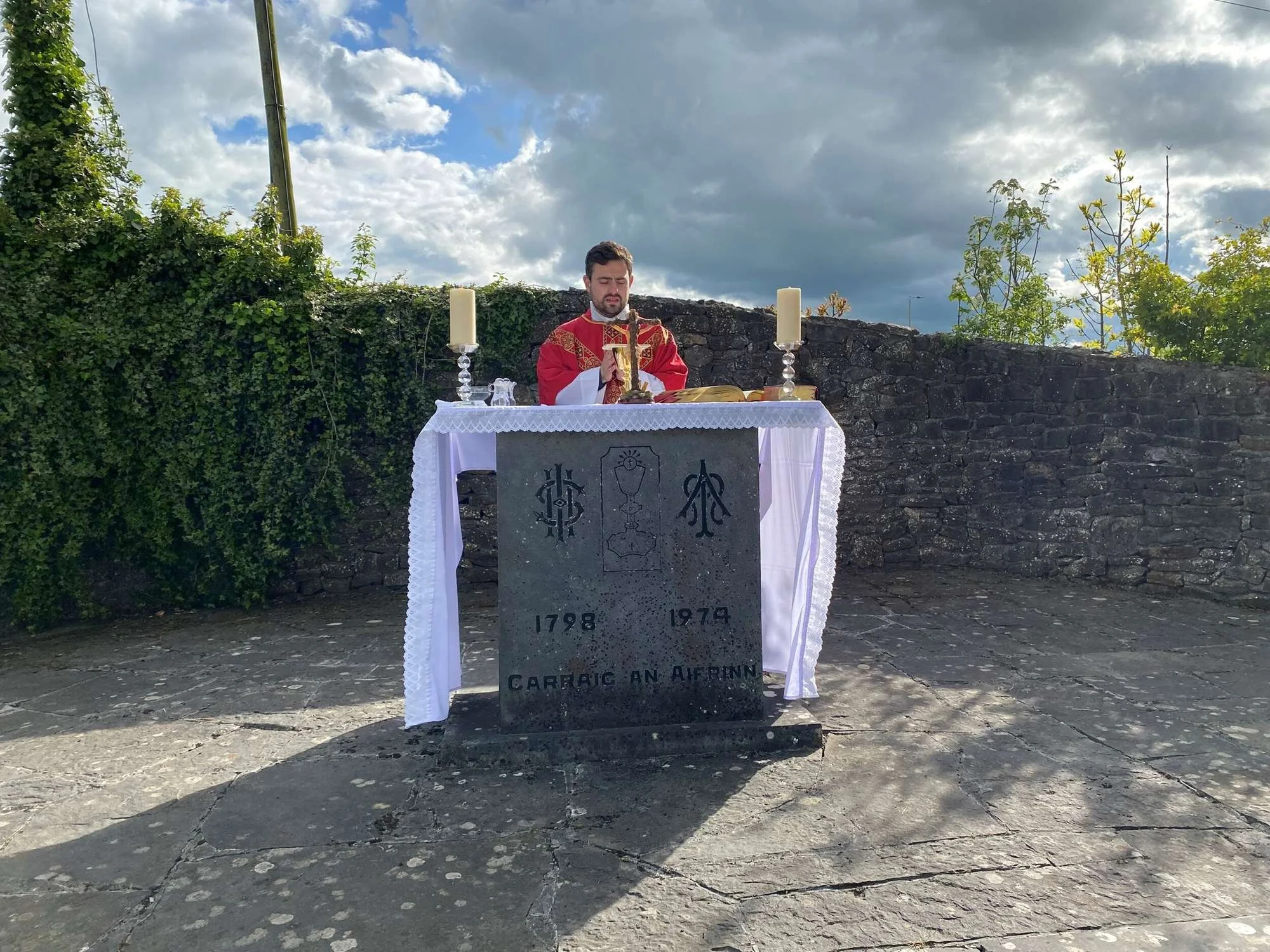A priest celebrates Mass behind an inscribed stone altar