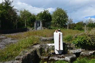 Fr Mark Condon raises the host at a garden Mass Rock