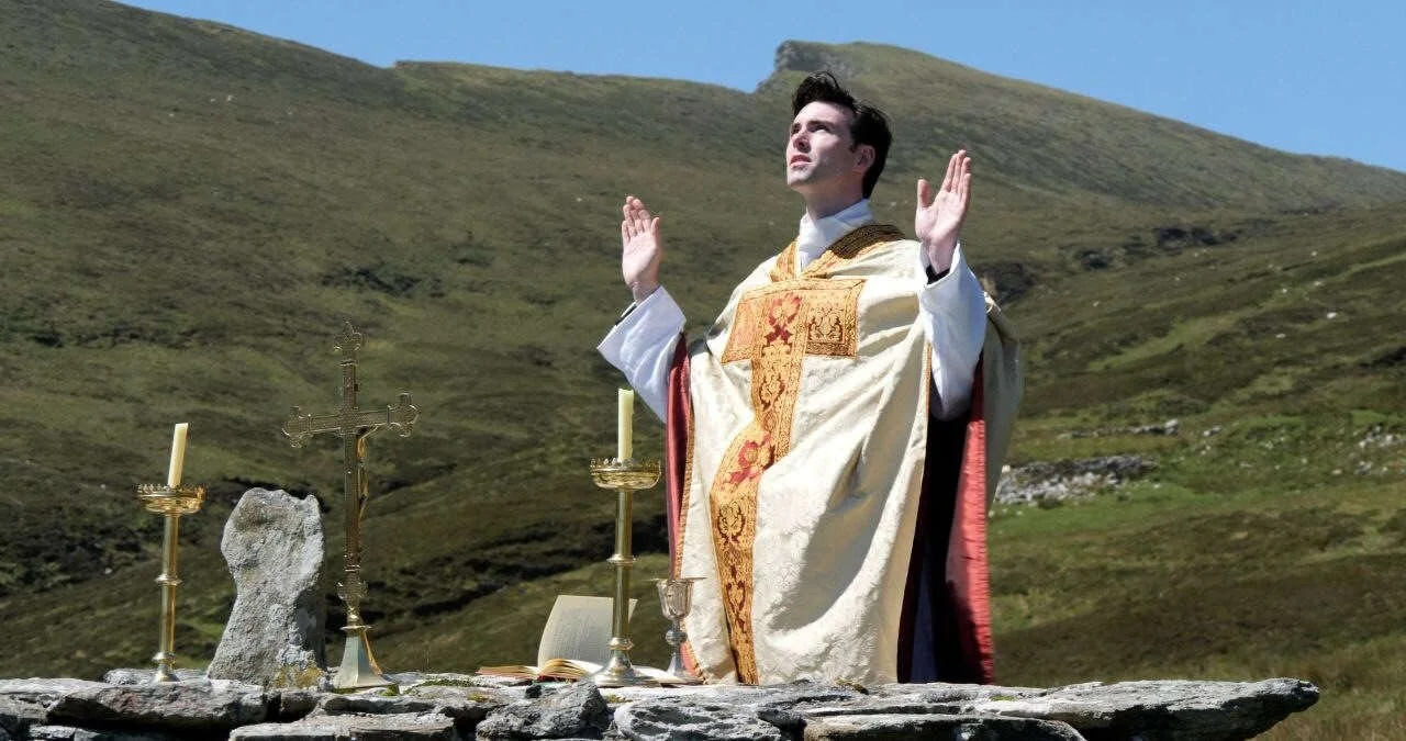 A priest prays at a hillside Mass Rock altar