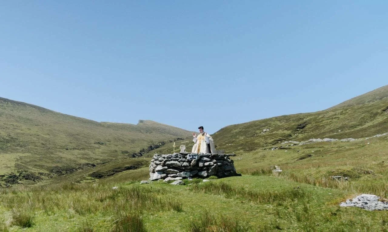 Wide view of a priest at a hillside stone altar