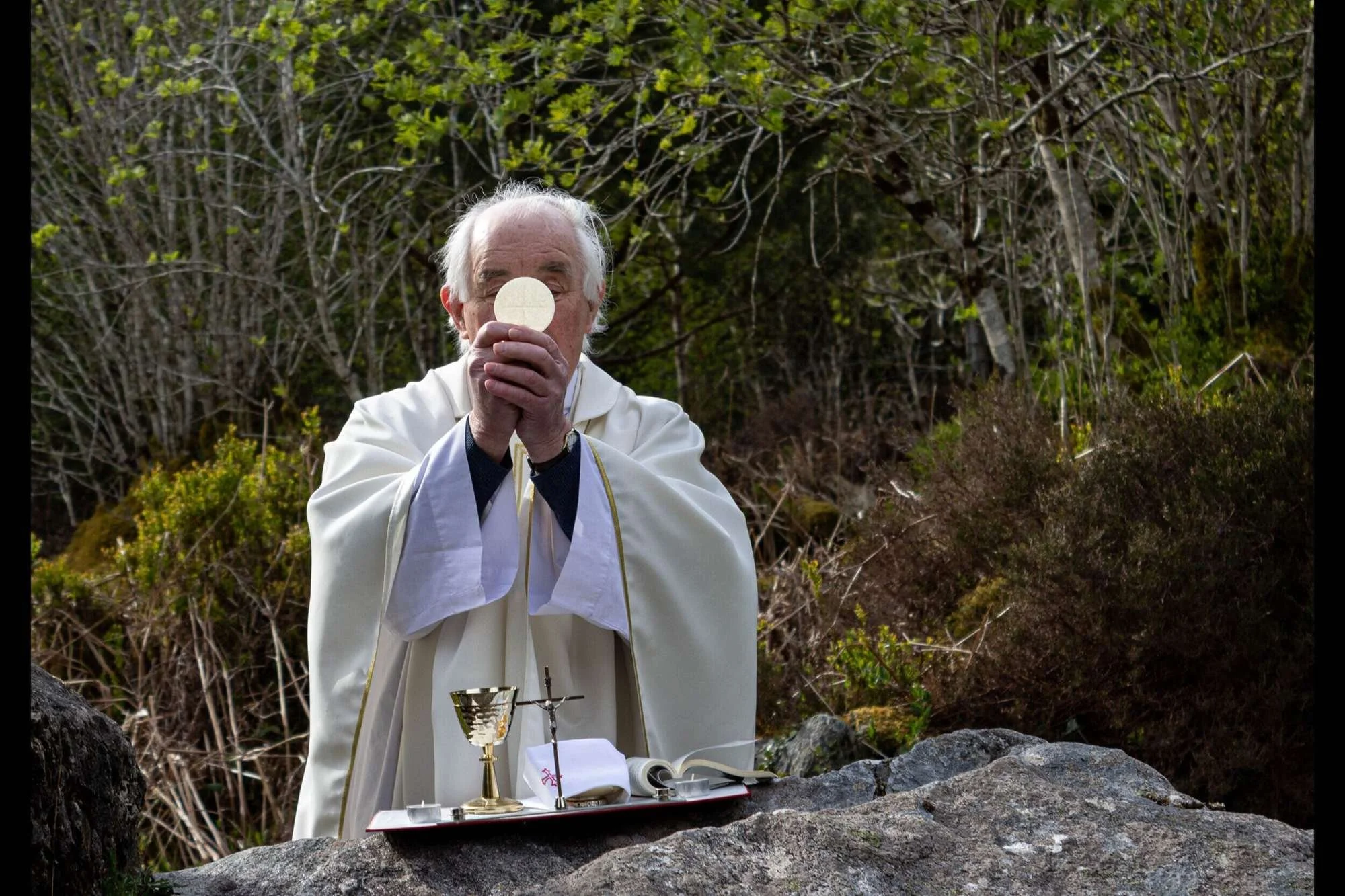 Fr Tommy Johnston raises the host at Mass Hill