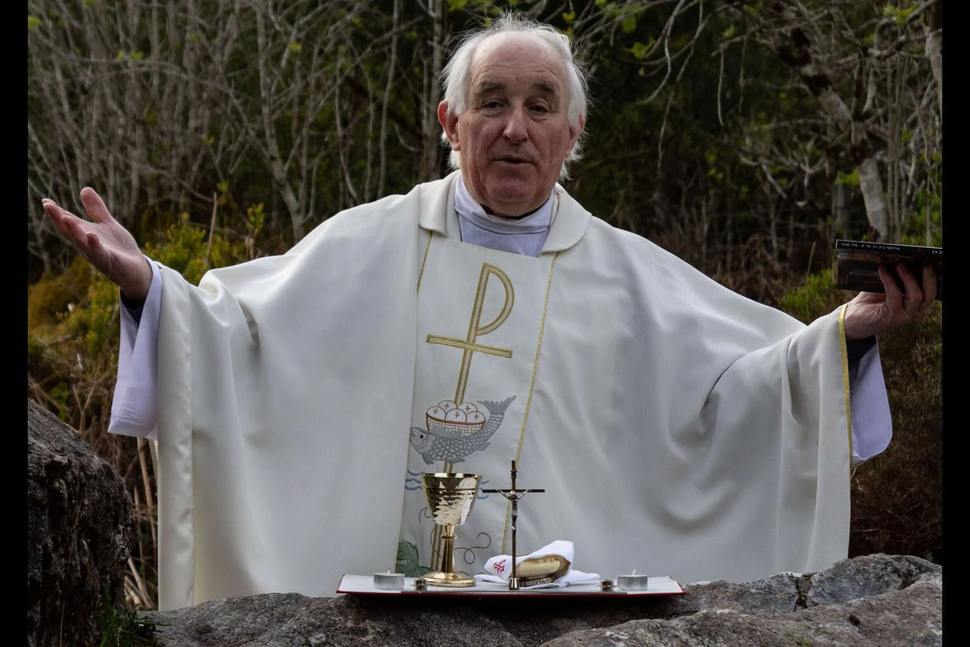 Fr Tommy Johnston prays with open hands at Mass Hill
