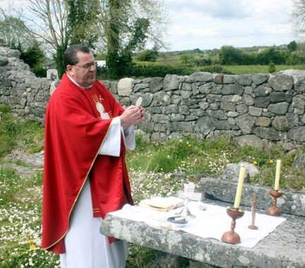 Fr Robert McNamara holds the host at a Moycullen Mass Rock