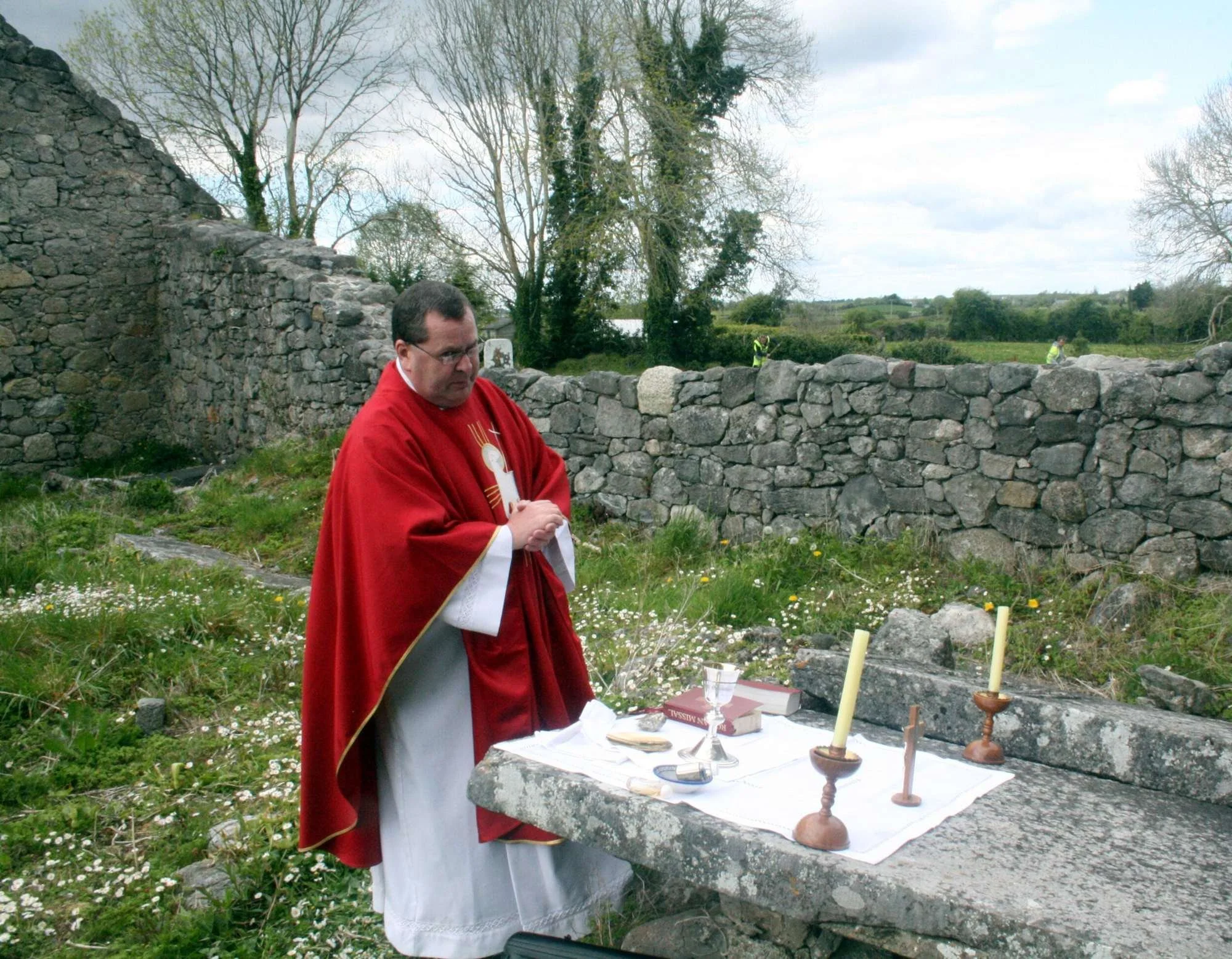 Fr Robert McNamara bows beside a stone altar in Moycullen