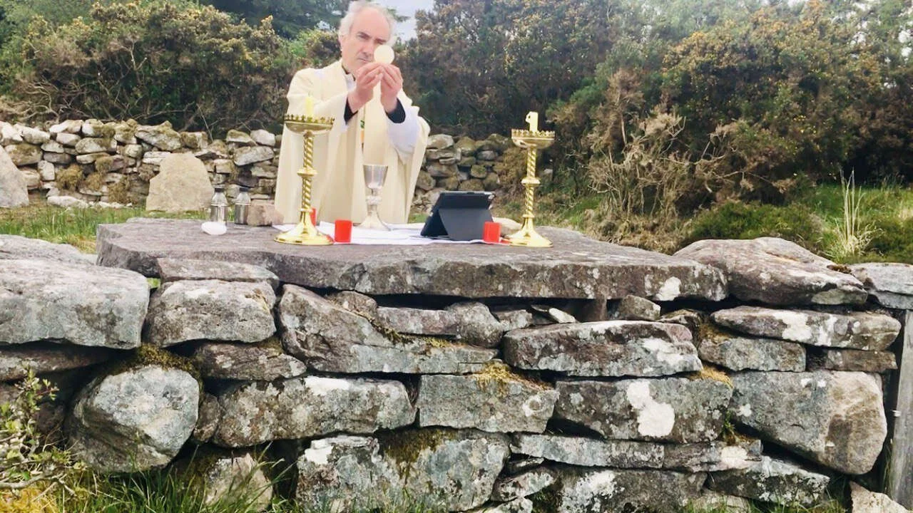Fr Kieran O’Rourke raises the host at Loughatorick Mass Rock in Woodford