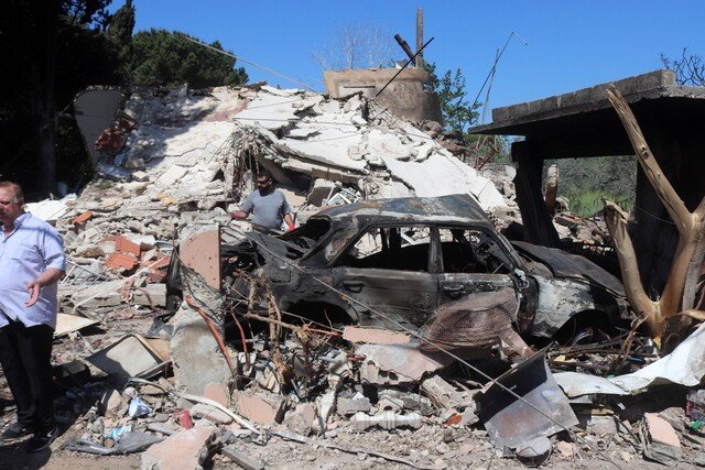 Site where a rocket exploded with people walking through the rubble