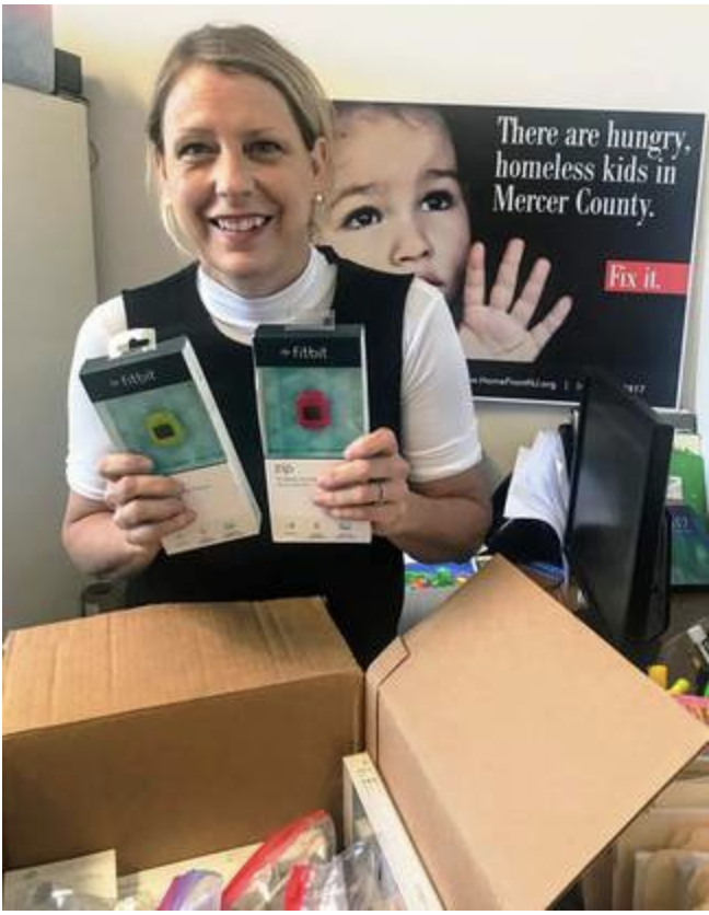 Liza Peck, support services liaison for HomeFront Family Campus, opens a box of new and refurbished trackers.