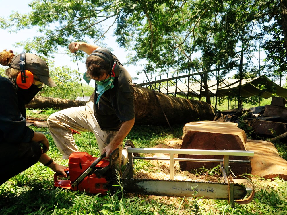 Long-time team members Shani and Charlie start up the Husqvarna chainsaw on site at Astillero Verde , in preparation to cut sustainably-sourced tropical hardwoods with the Granberg Int’l Alaskan Chainsaw Mill. The shipbuilding hangar and lofting floor can be seen in the background. Photo: Danielle Doggett