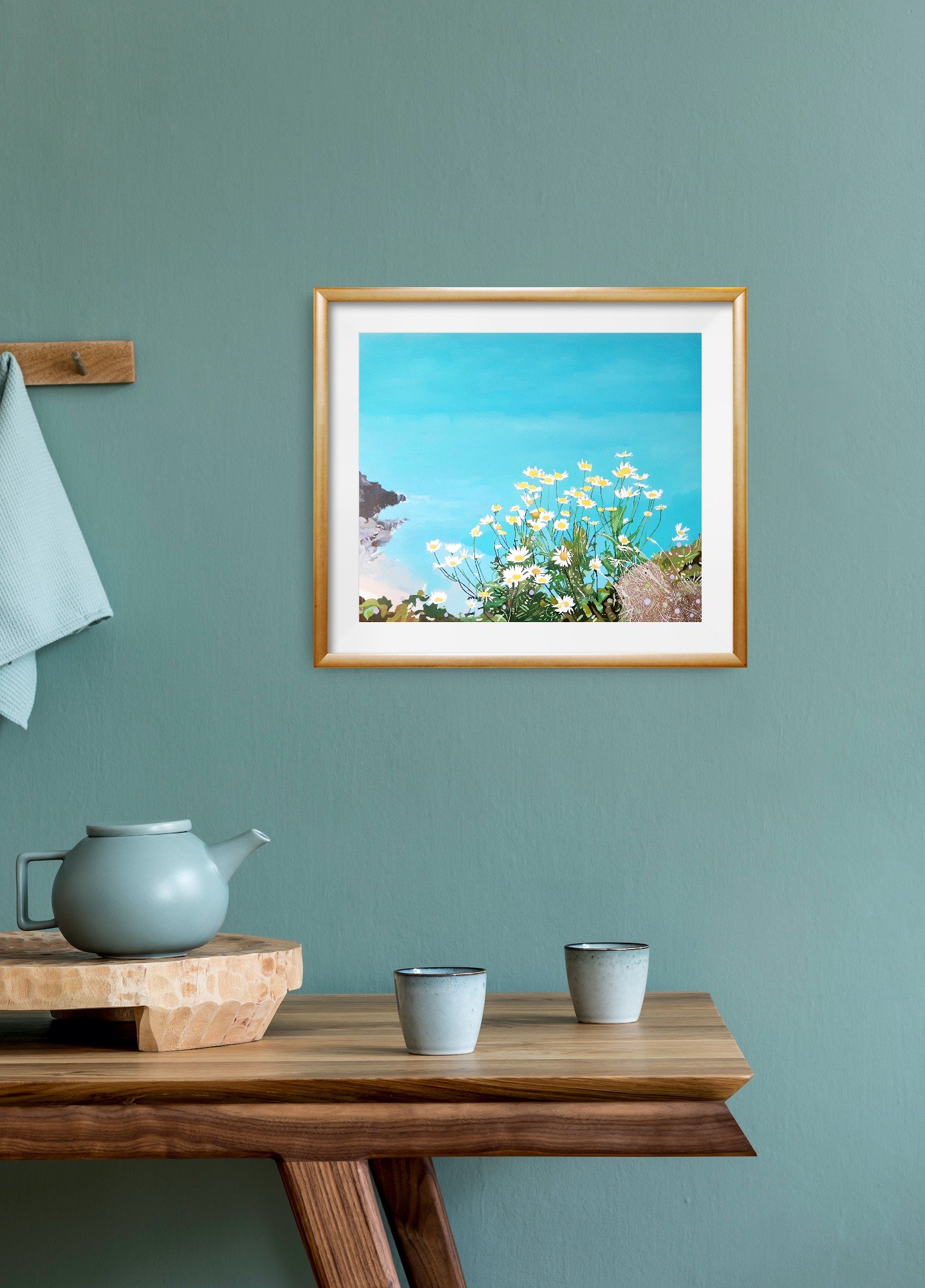 A framed art print of daisies on a Cornish cliff, looking out to sea displayed on a wall (Copy)