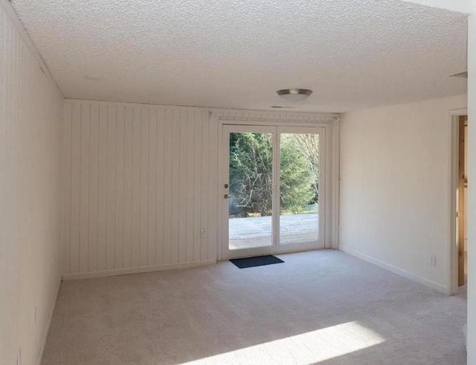 New carpeted master bedroom with double door leading to deck overlooking backyard.