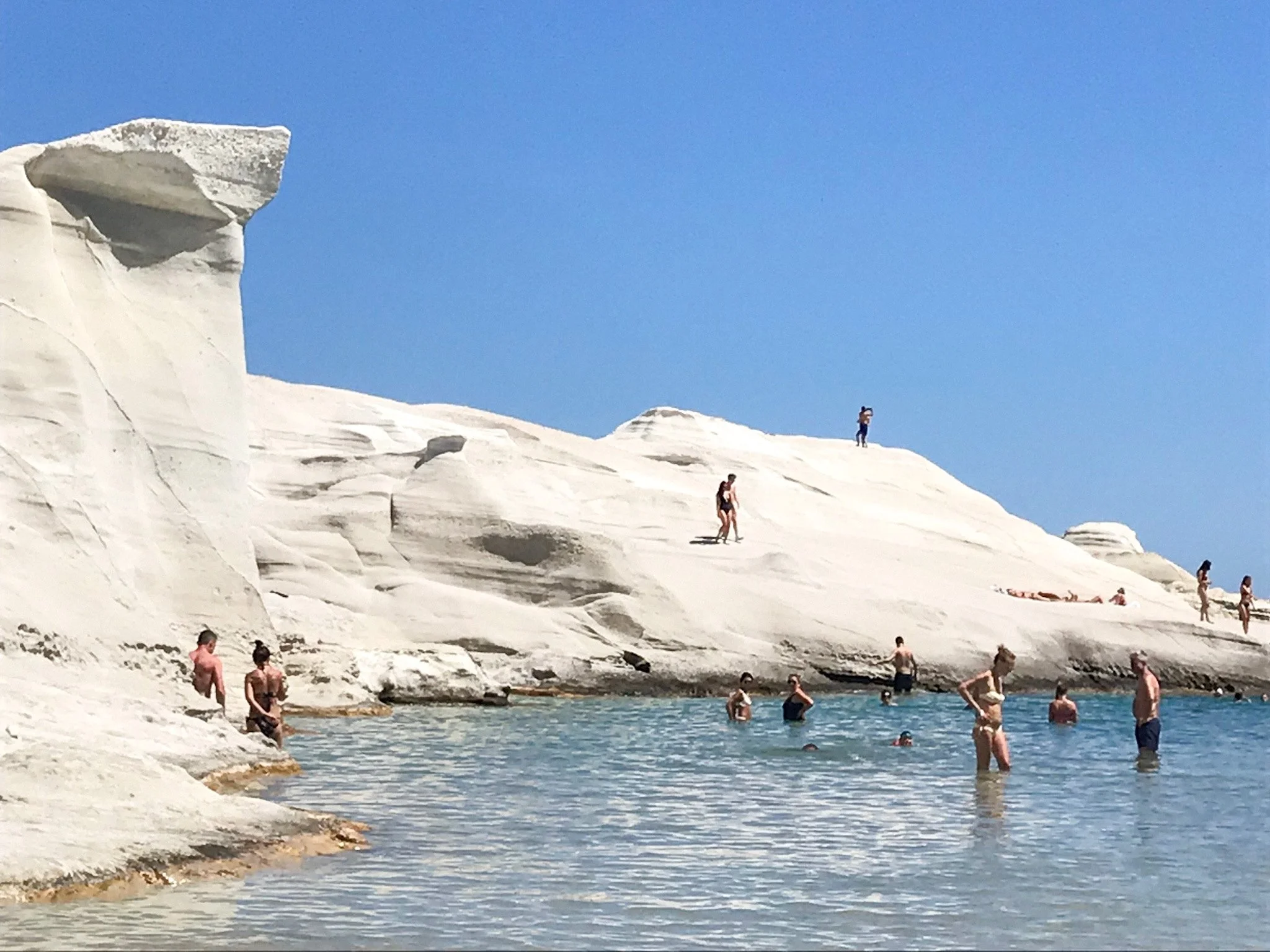 Sarakiniko beach Milos white rocks. with people swimming
