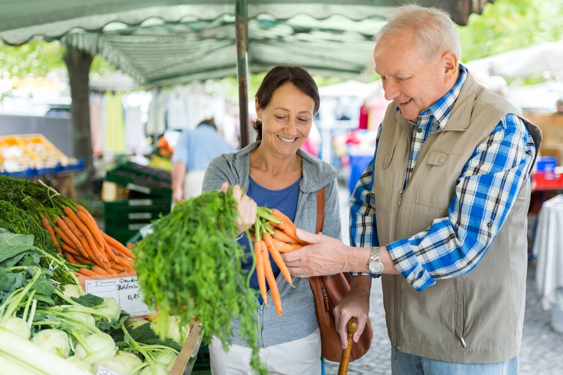 CAREgiver helping a senior client pick out fresh vegetables at a local farmers market