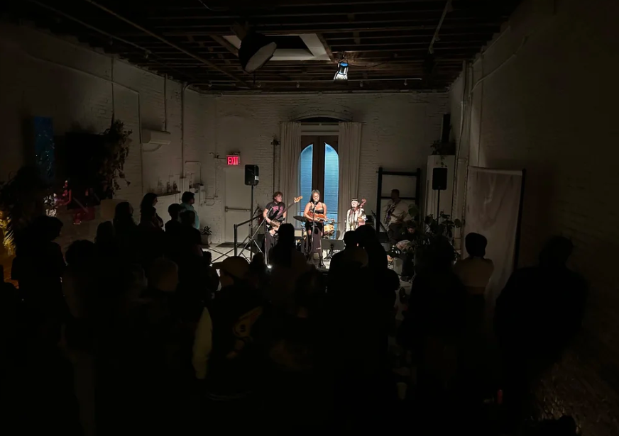 An indoor concert with four musicians playing in front of a full-room audience