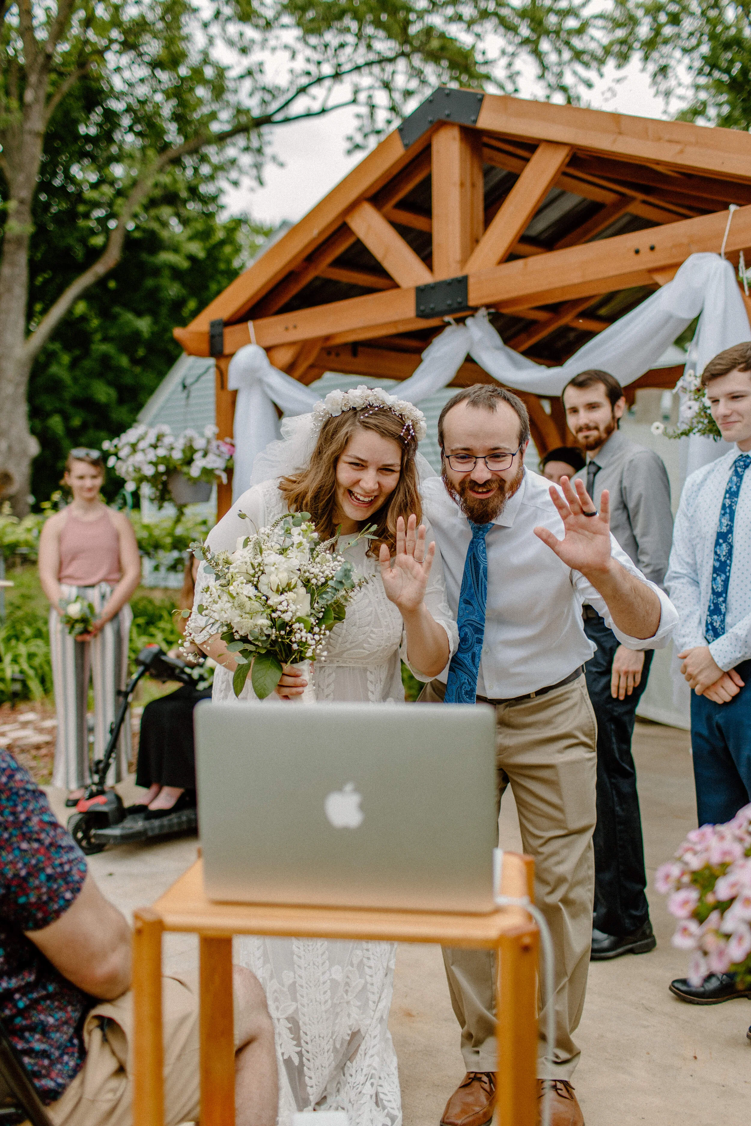 bride and groom wave to their long distance zoom wedding guests at cute backyard wedding in minneapolis minnesota, covid wedding