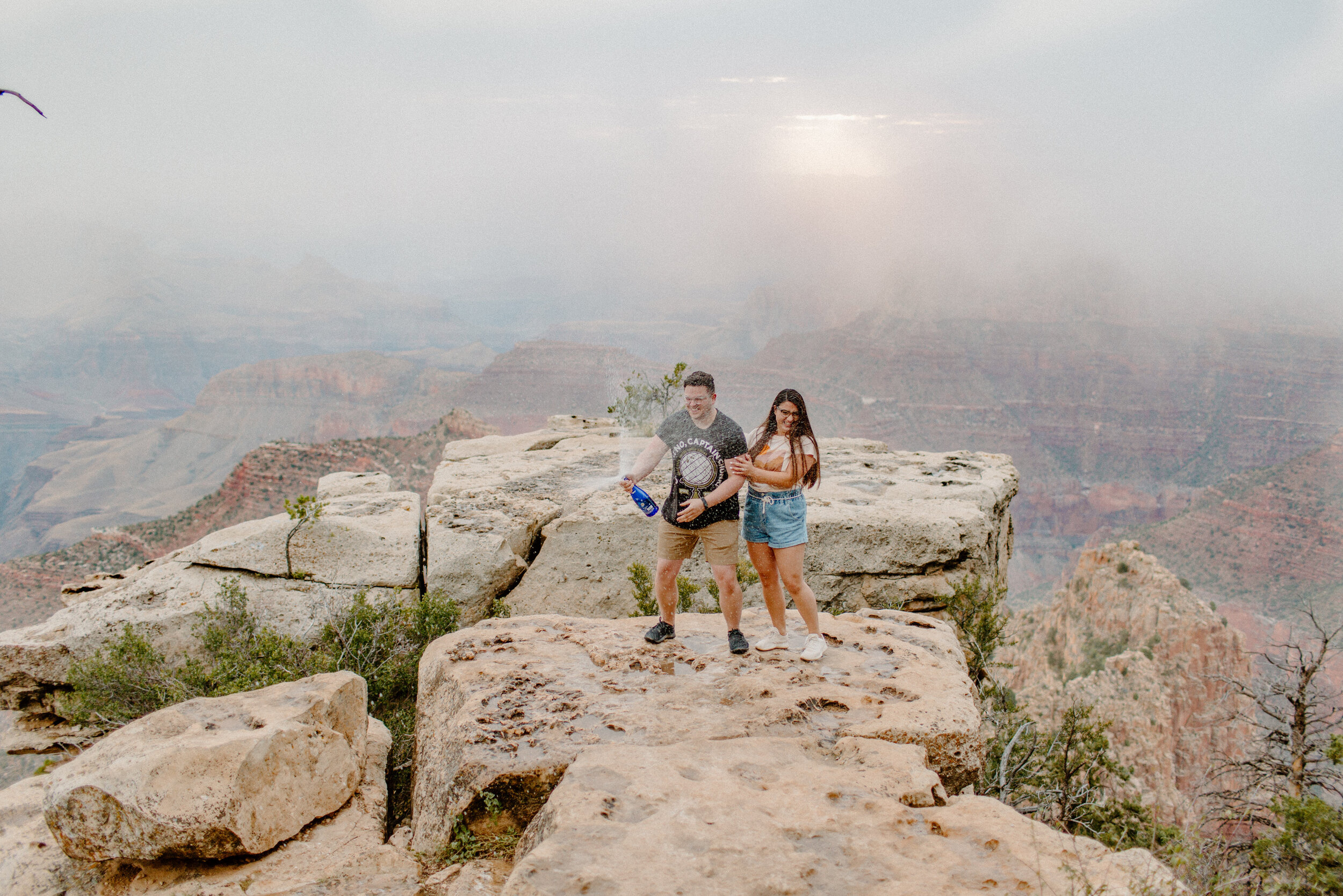 couple pops a bottle of champagne after getting engaged at the grand canyon south rim, grand canyon engagement photographer